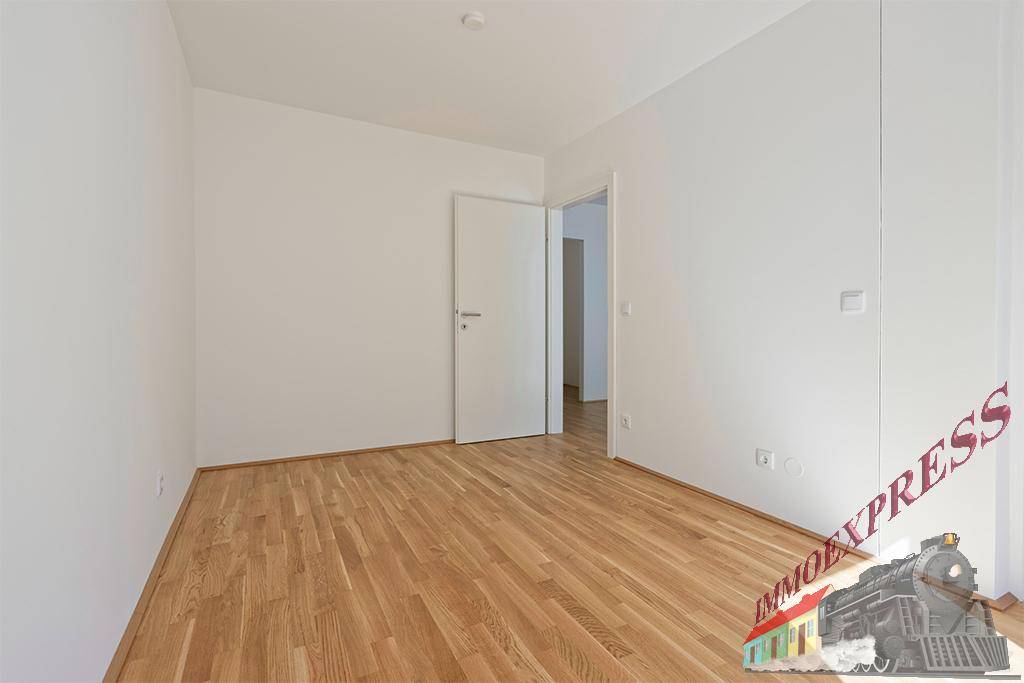 Leeres Zimmer mit Parkettboden und weiß gestrichenen Wänden, bereit zur individuellen Gestaltung.