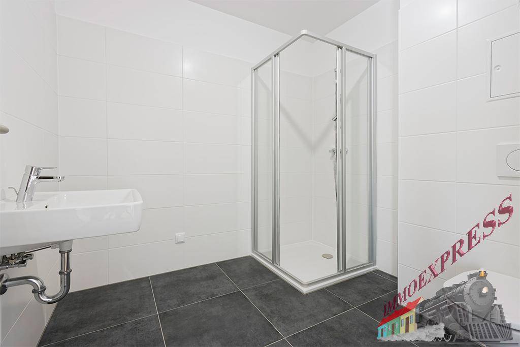Modernes Badezimmer mit weißen Fliesen, dunklem Boden und einer Duschkabine.