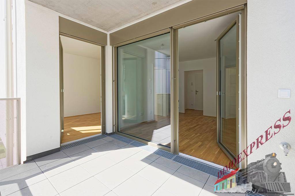 Geräumiger Balkon mit Fliesenboden und Zugang zu den Innenräumen durch große Glastüren.