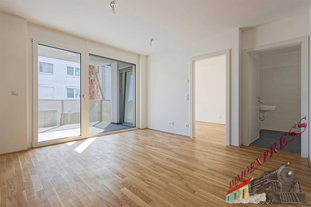 Helles Wohnzimmer mit Parkettboden und großem Fenster, das Zugang zu einem Außenbereich bietet.