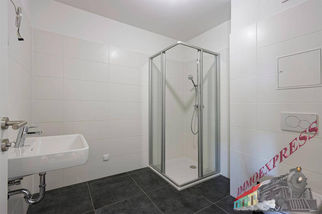 Modernes Badezimmer mit Duschkabine, Waschbecken und weißen Fliesen an den Wänden.