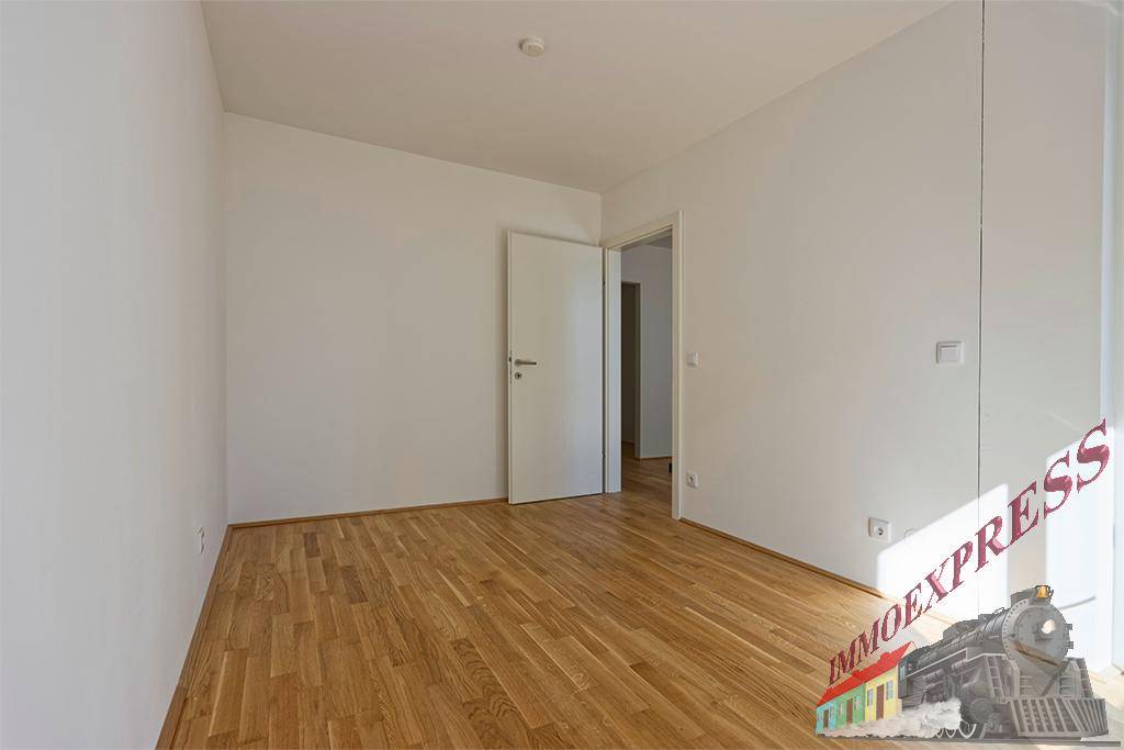 Ruhiges Schlafzimmer mit hellem Parkettboden und weiß gestrichenen Wänden, bereit zur Einrichtung.
