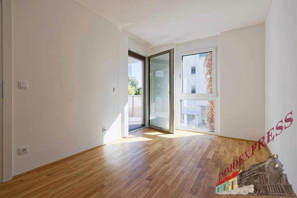 Lichtdurchfluteter Raum mit Parkettboden und Zugang zu einem Balkon, ideal für entspannte Stunden.
