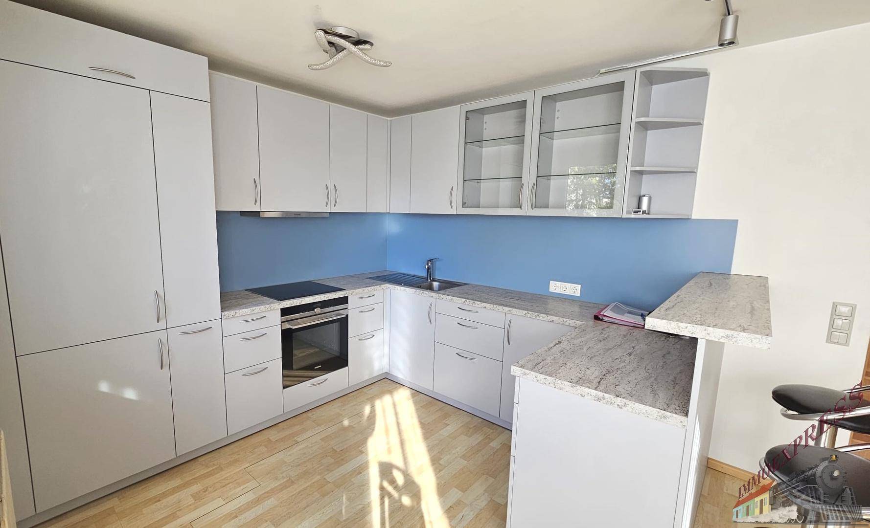 Moderne Einbauküche mit hellen Schränken, Granitarbeitsplatte und blauer Rückwand.