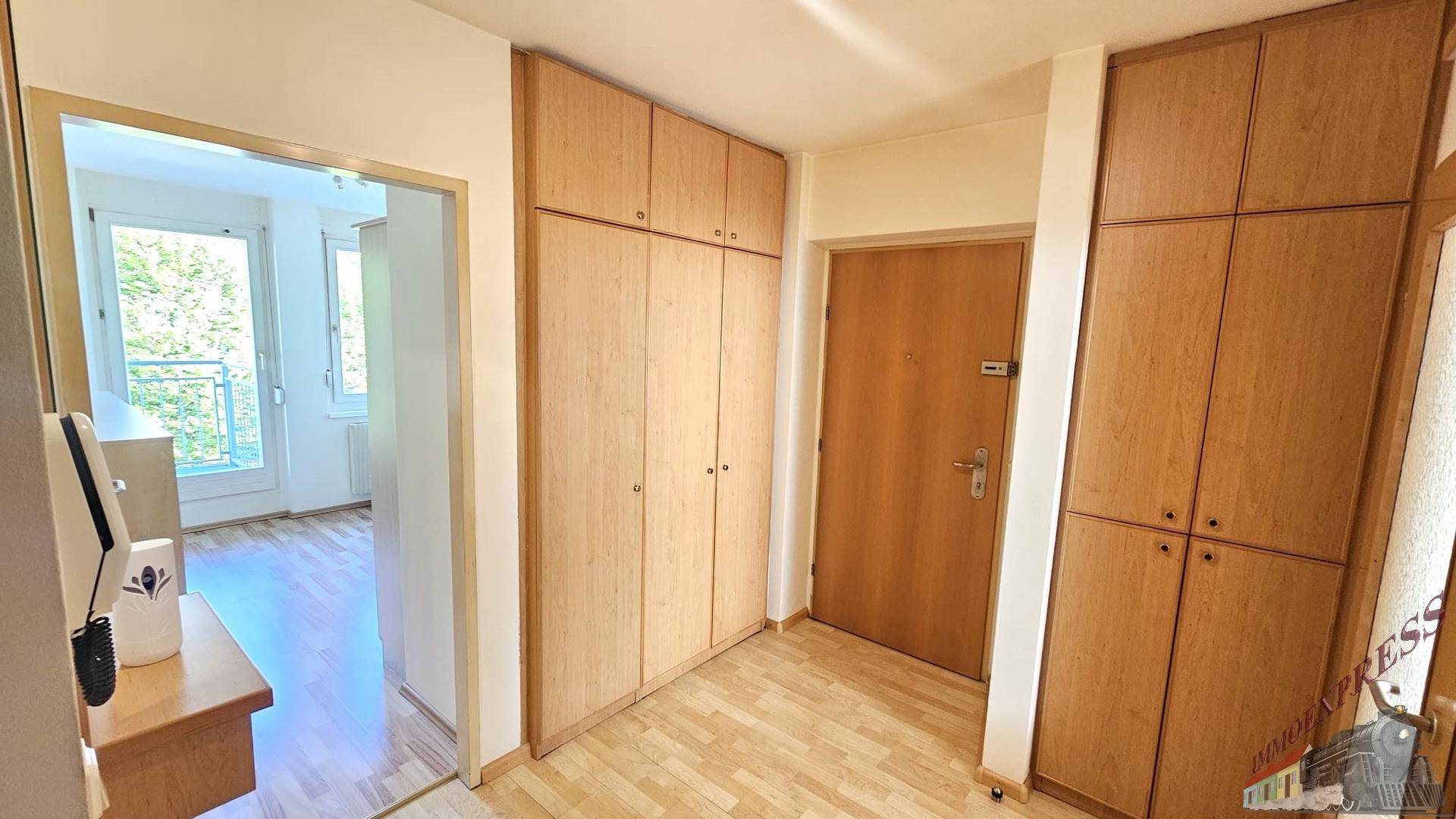 Flur mit praktischen Einbauschränken aus Holz und hellem Holzboden.