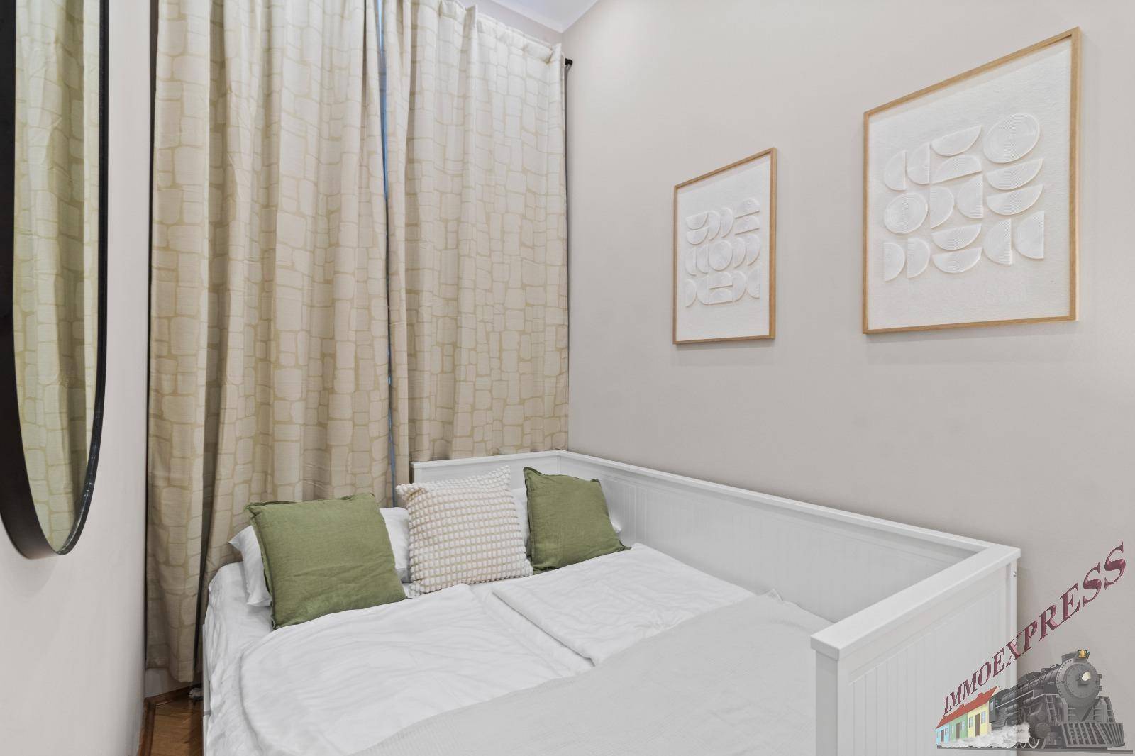 Helles Schlafzimmer mit schlichtem Einzelbett, beigen Vorhängen und minimalistischer Wandkunst für eine ruhige Atmosphäre.