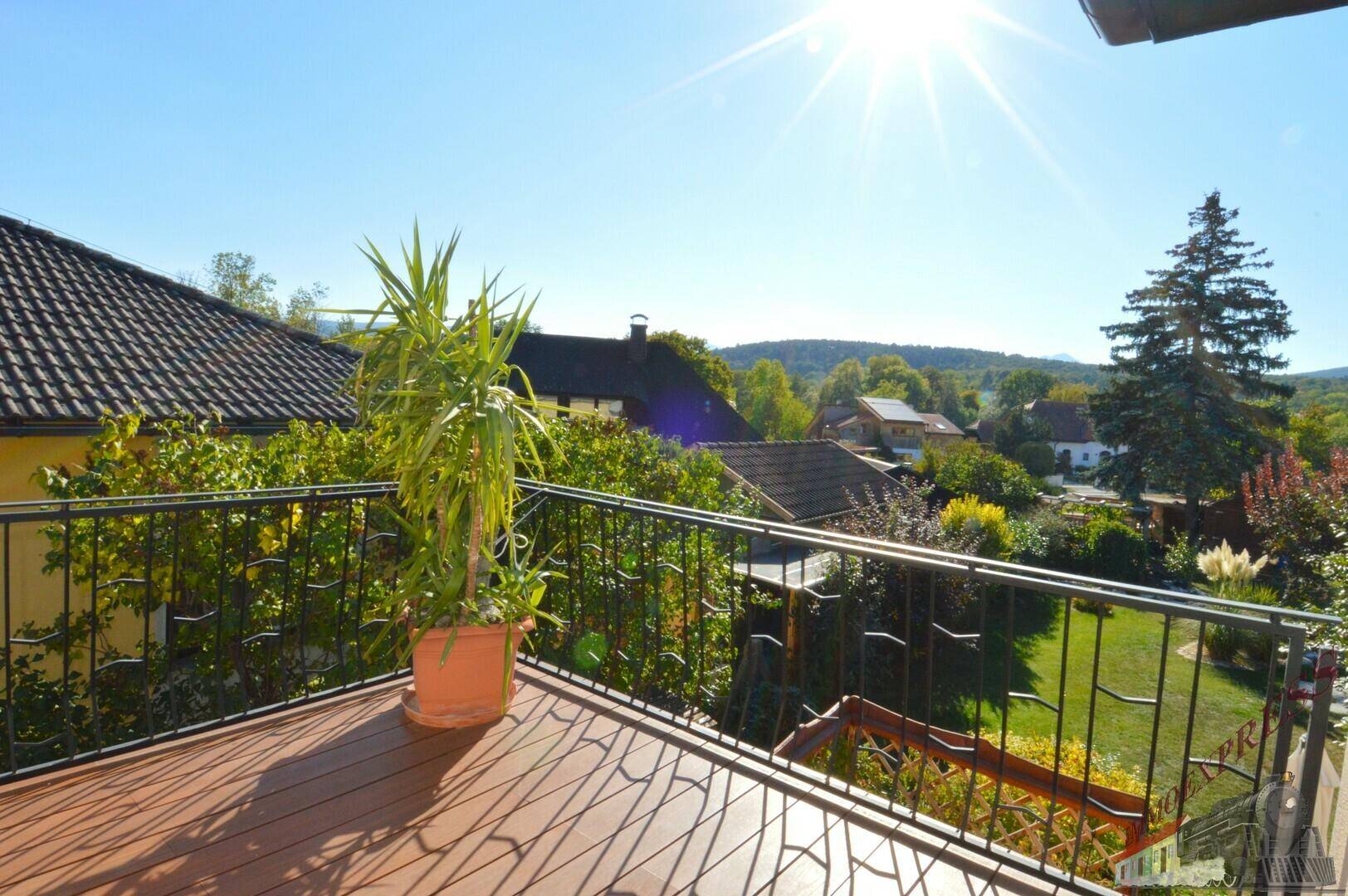 Blick vom Balkon über die Dächer der Nachbarschaft und die umliegende grüne Hügellandschaft.