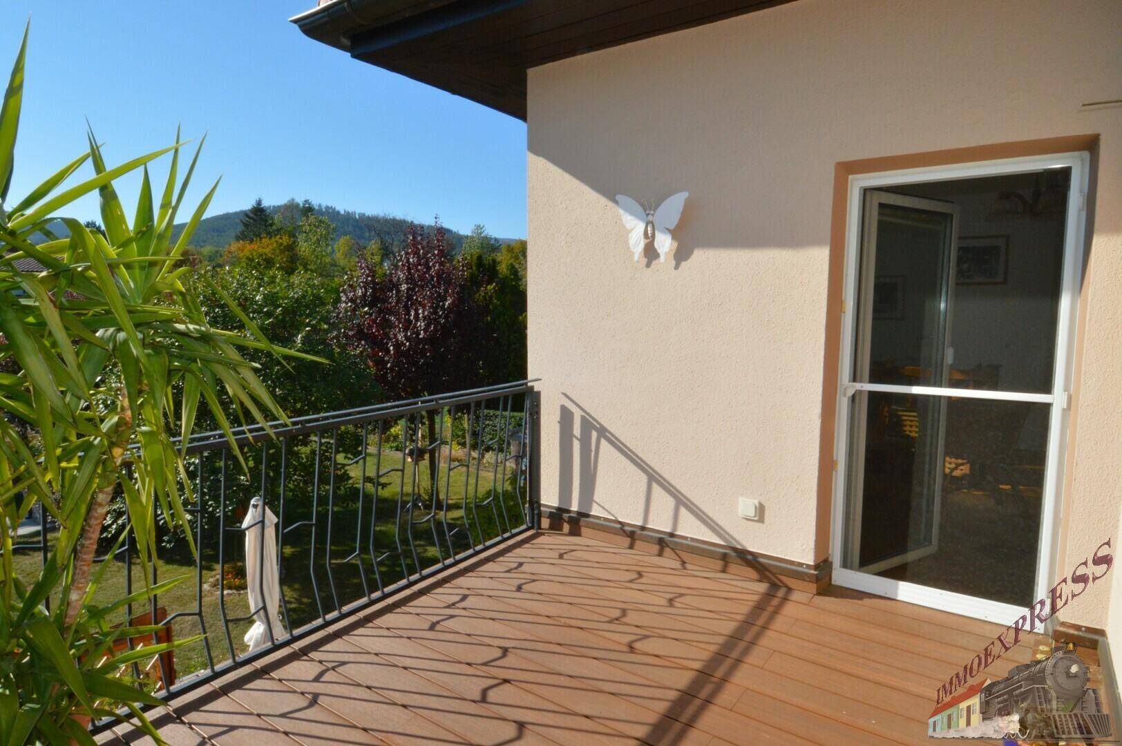 Sonniger Balkon mit Metallgeländer und weitem Blick auf die grüne Umgebung.
