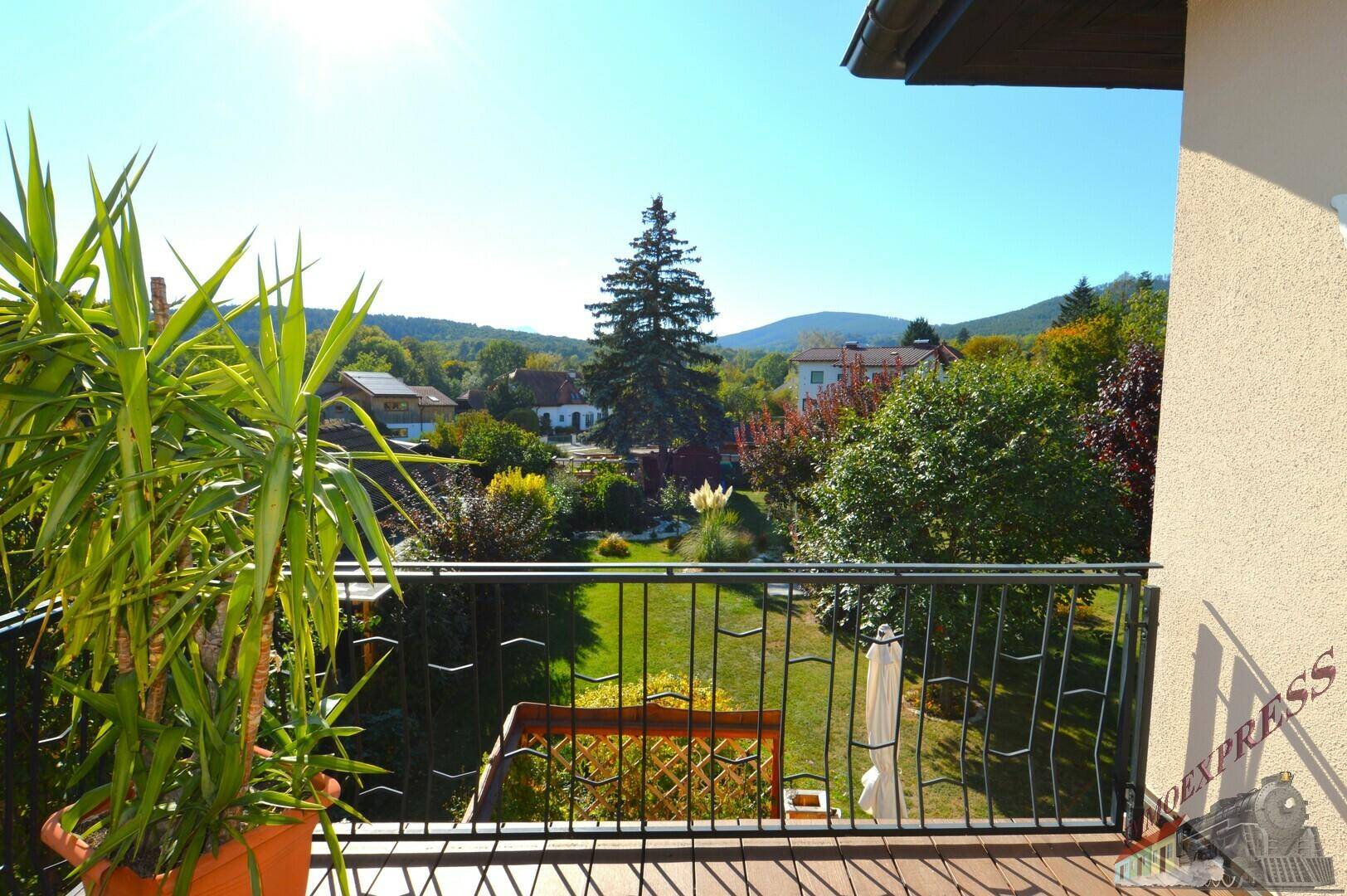Balkon mit weitem Blick über die grüne Landschaft und die umliegenden Häuser.