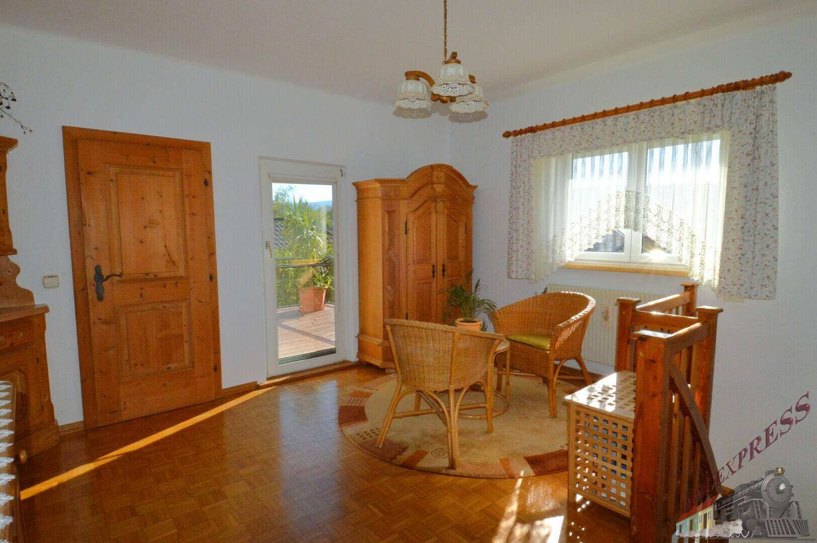 Helles Zimmer mit Parkettboden, Holzmöbeln und Zugang zum sonnigen Balkon.