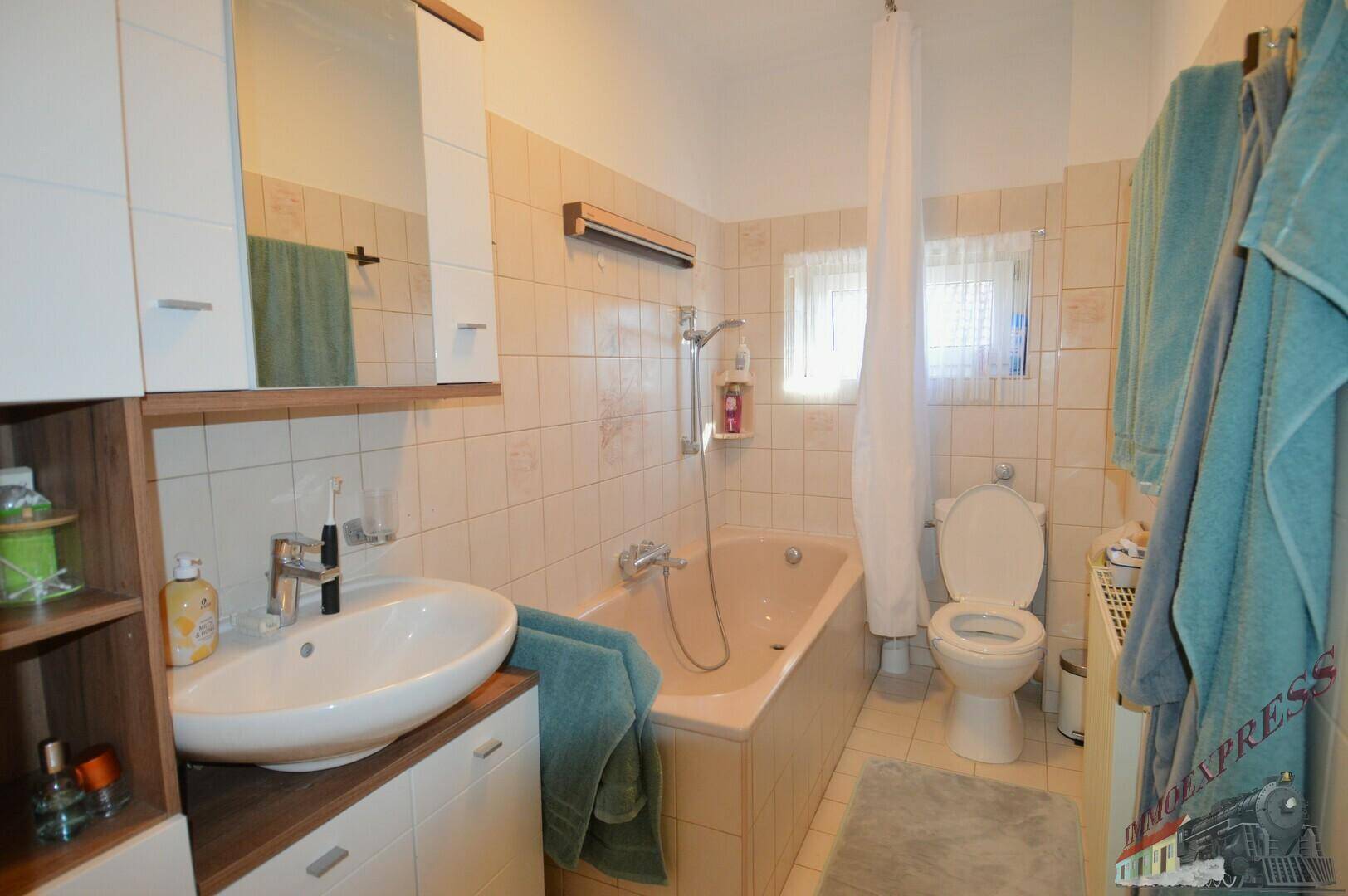 Badezimmer mit Badewanne, Waschbecken, WC und hellen Fliesen, in gutem Zustand.
