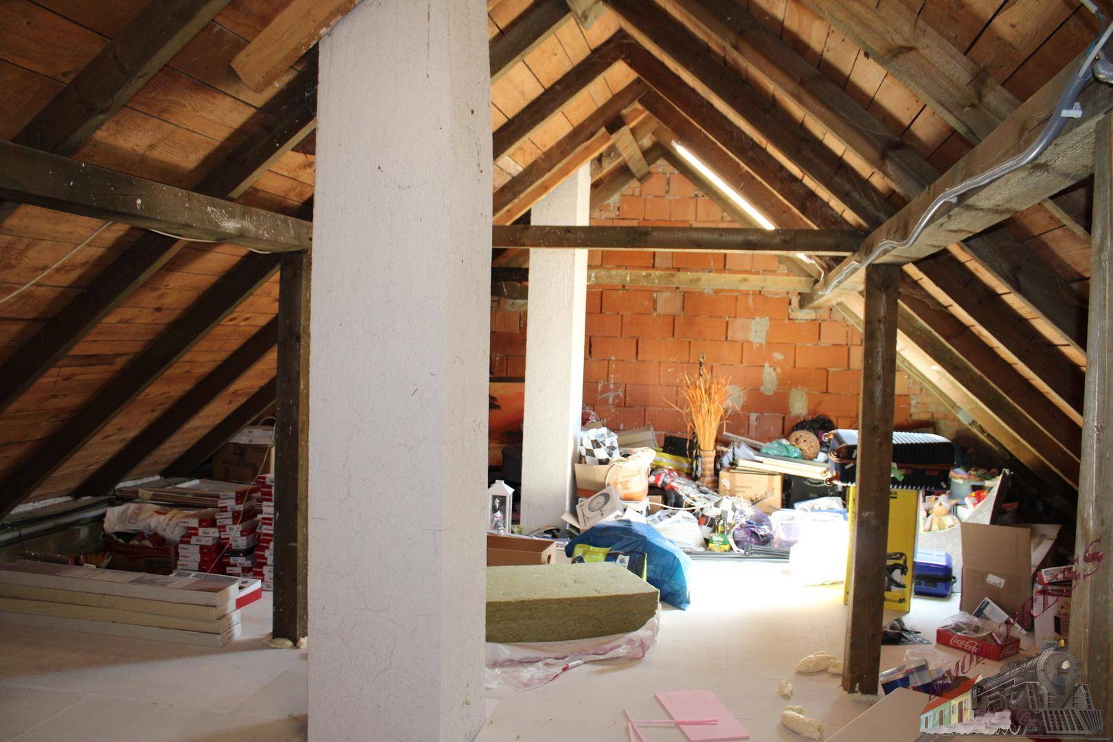 Unausgebauter Dachboden mit sichtbaren Holzbalken und Ziegelwänden, bietet Ausbaupotenzial.