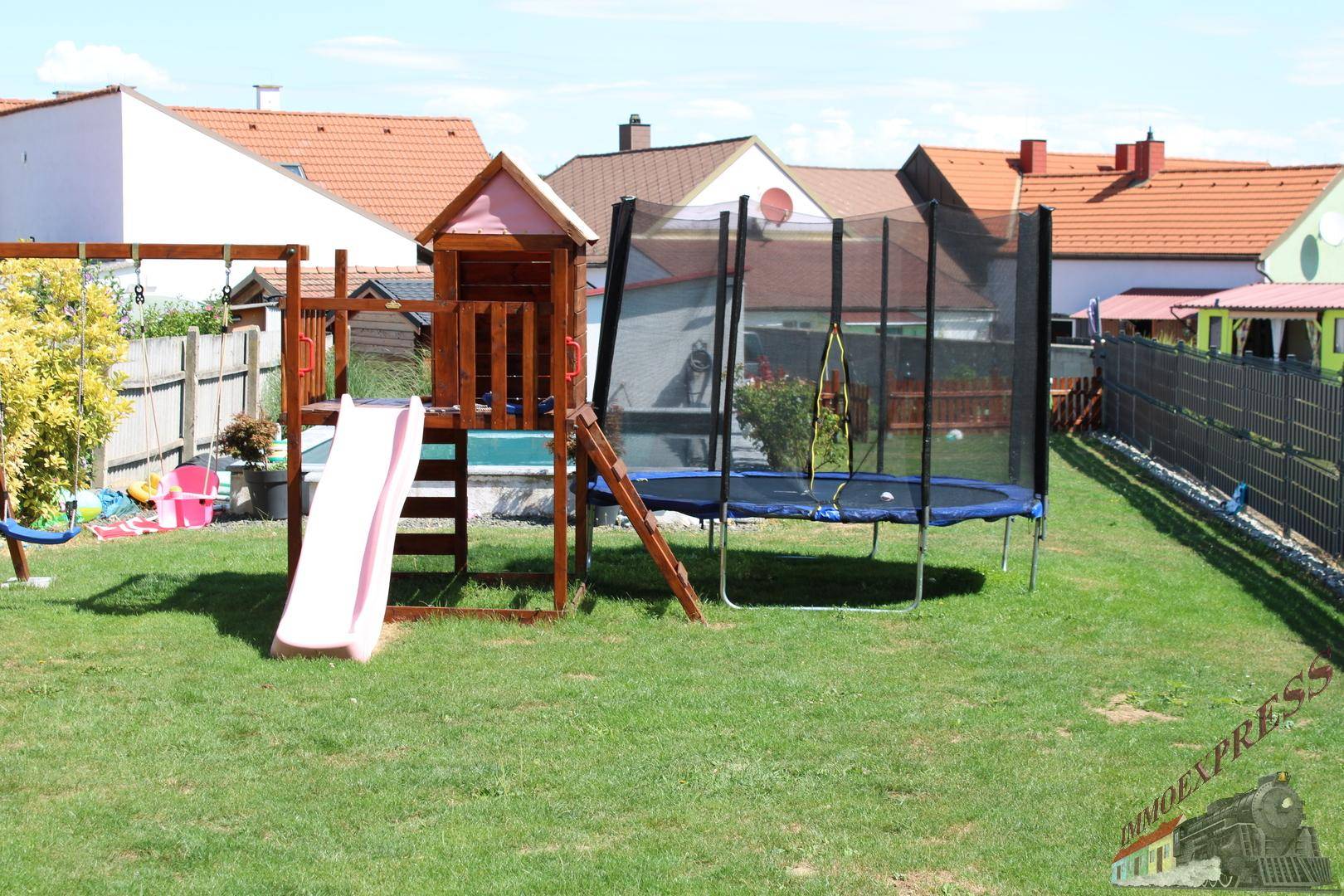 Detailansicht des Spielplatzes im Garten mit Rutsche, Schaukel und Trampolin.