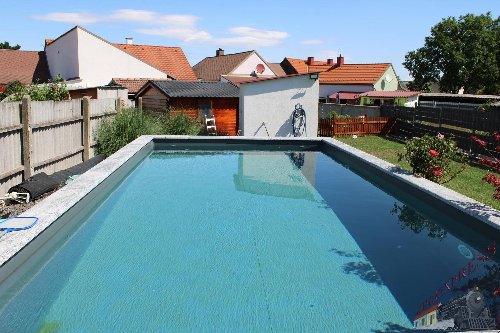 Großer, sauberer Außenpool im Garten mit klarem Wasser und Steinumrandung.