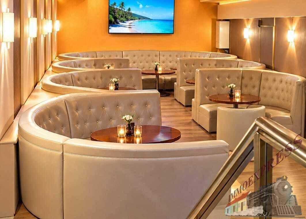 Stilvolle Lounge mit bequemen, geschwungenen Sitzgelegenheiten und einem großen Bildschirm für entspannte Stunden.