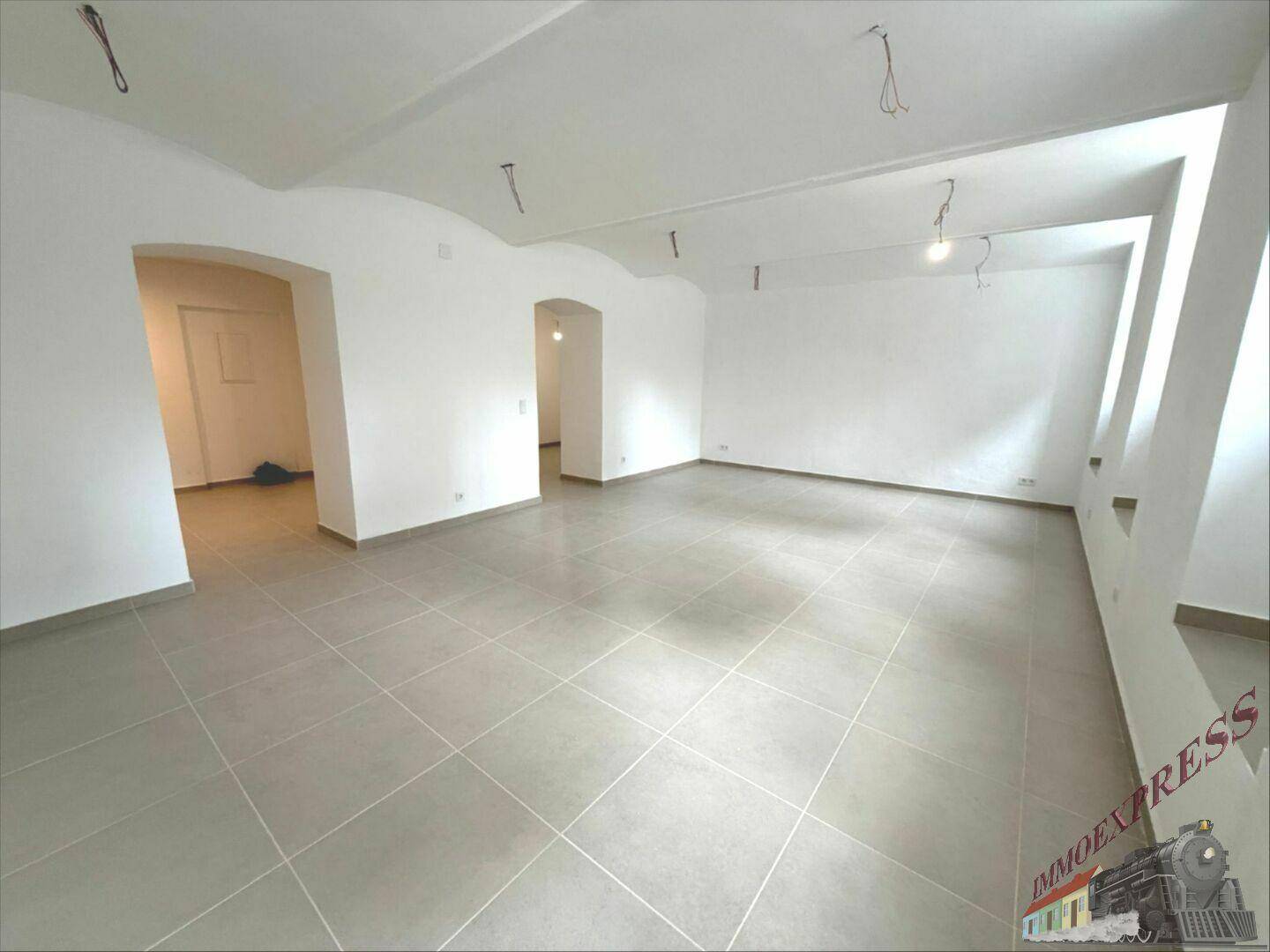 Weitläufiger Raum mit Fliesenboden, gewölbten Decken und mehreren Türbögen, die zu anderen Bereichen führen.
