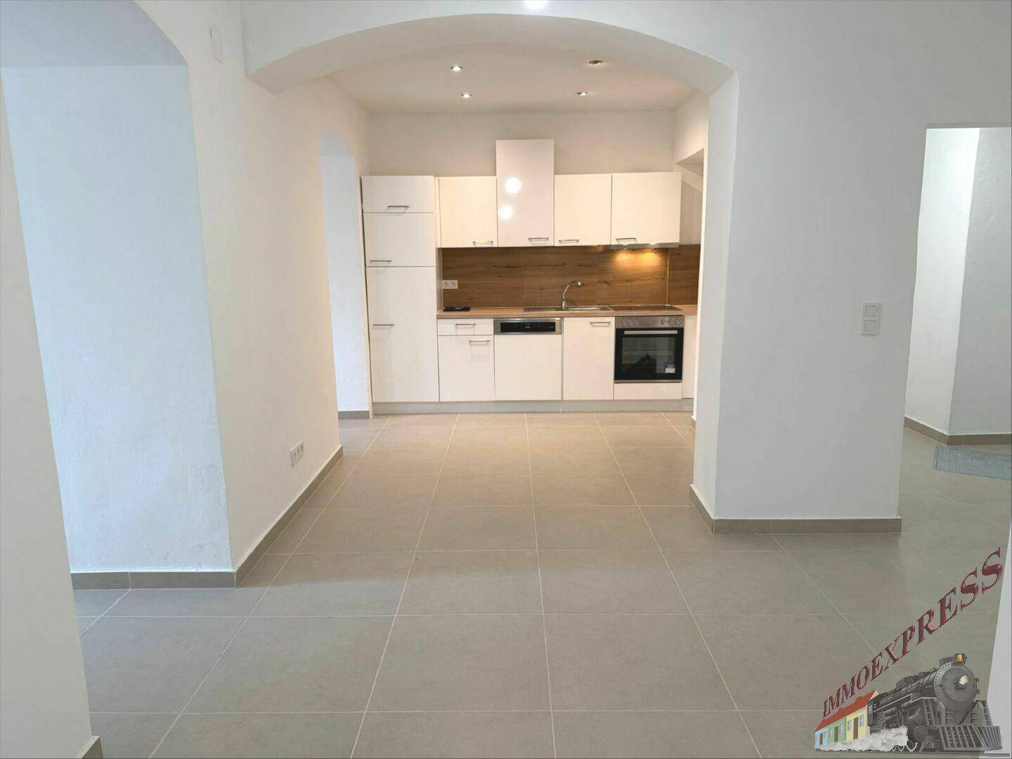 Geräumiger offener Wohnbereich mit integrierter Küche und einem eleganten Bogen als Übergang.