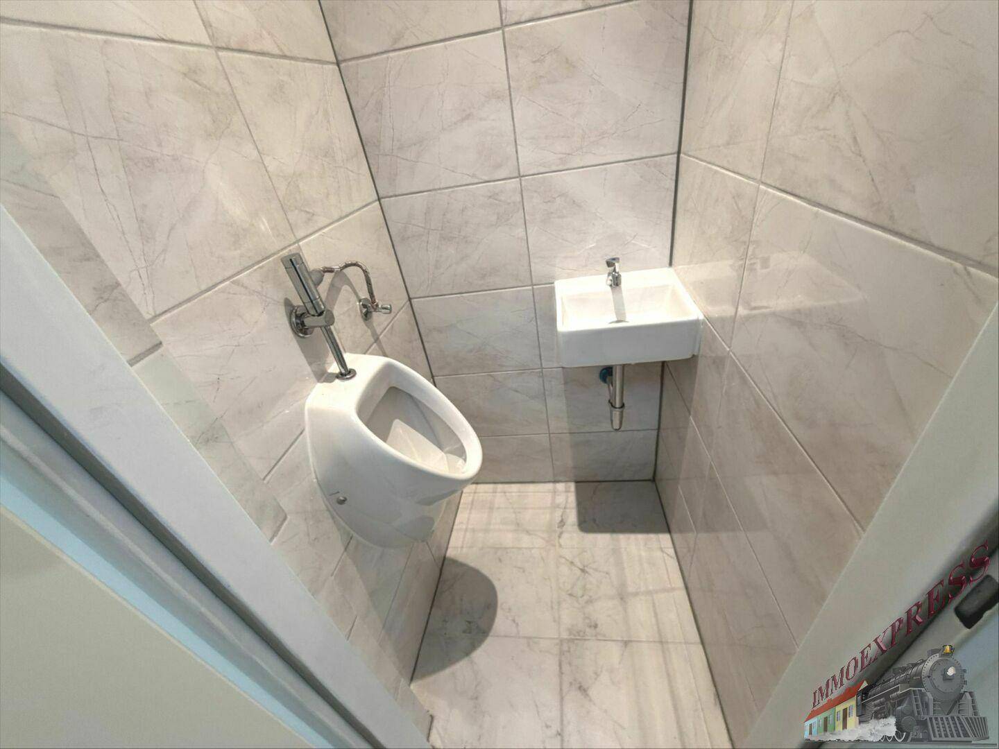 Modern geflieste Gästetoilette mit Urinal und kleinem Waschbecken in hellem Design.