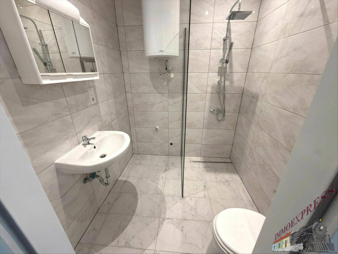 Modernes Badezimmer mit Duschkabine, Waschbecken und WC, komplett gefliest in hellen Tönen.