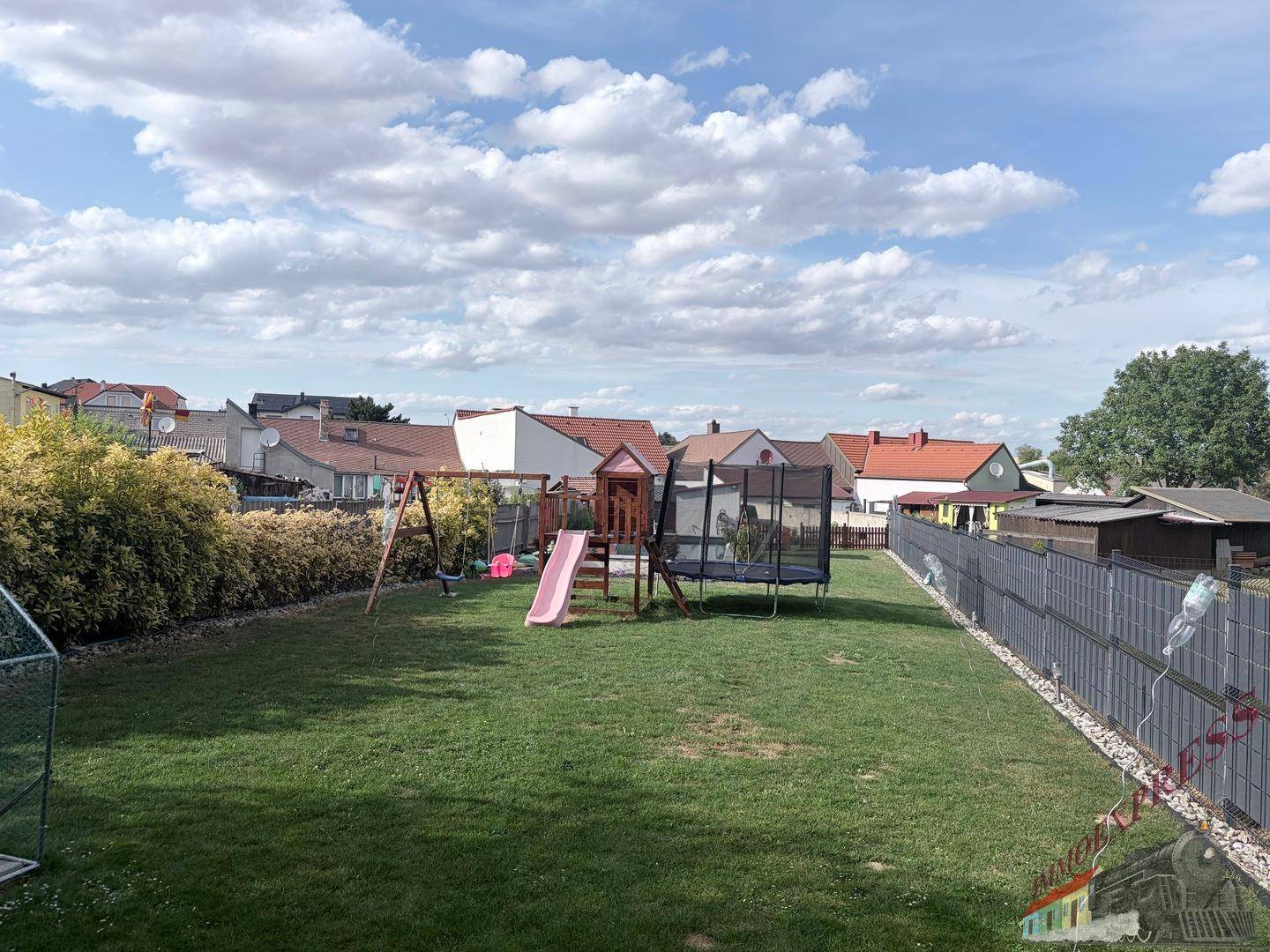 Großer Garten mit Rasenfläche, Spielplatz und Trampolin für Kinder.