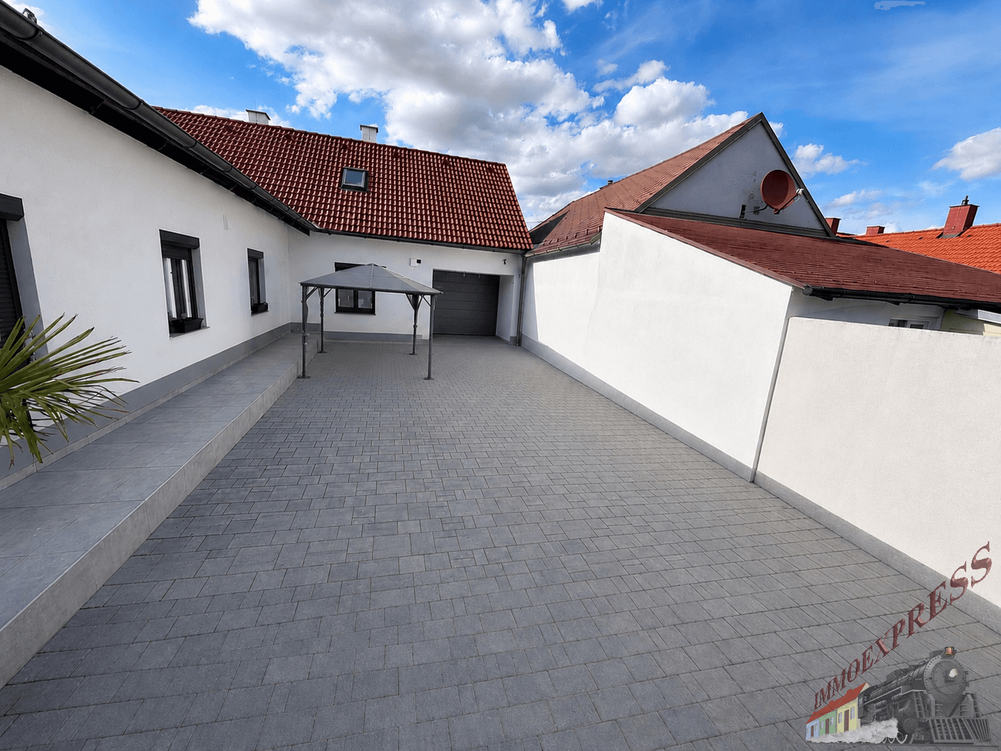 Breite gepflasterte Zufahrt zum Haus mit einem Pavillon und viel Platz.