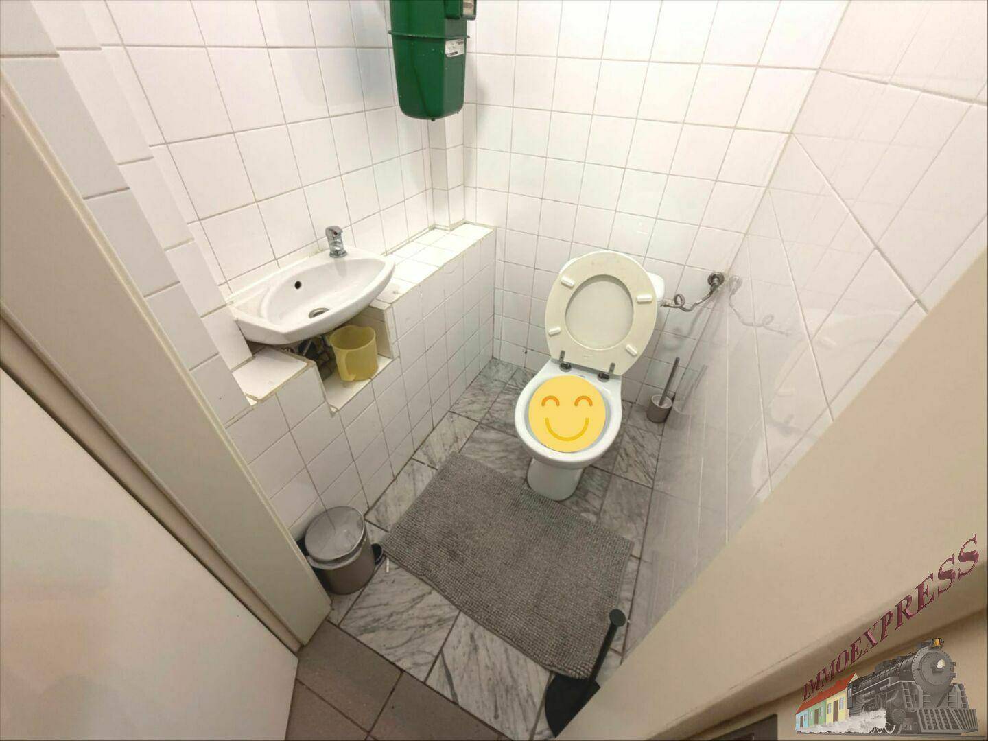 Kleines Badezimmer mit WC, Waschbecken und weißen Fliesen an Wänden und Boden.
