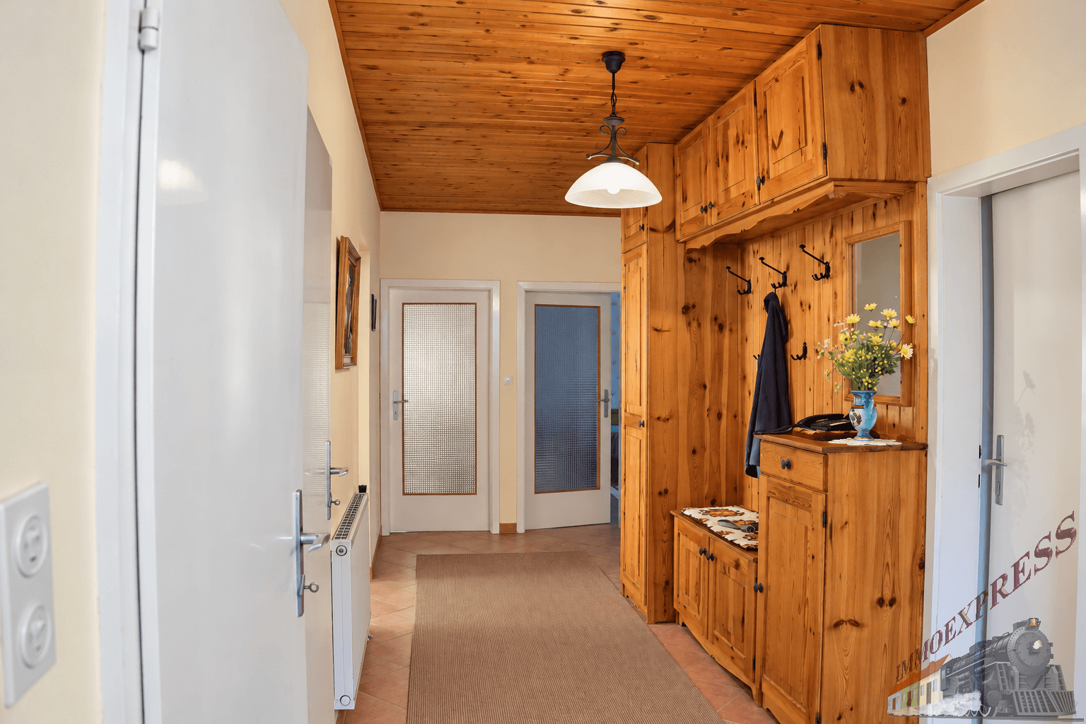 Flur mit Holzdecke, rustikaler Garderobe und Terrakotta-Fliesenboden.