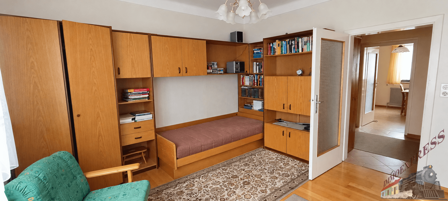 Schlafzimmer mit integriertem Bett, Holzmöbeln und einem gemusterten Teppichboden.