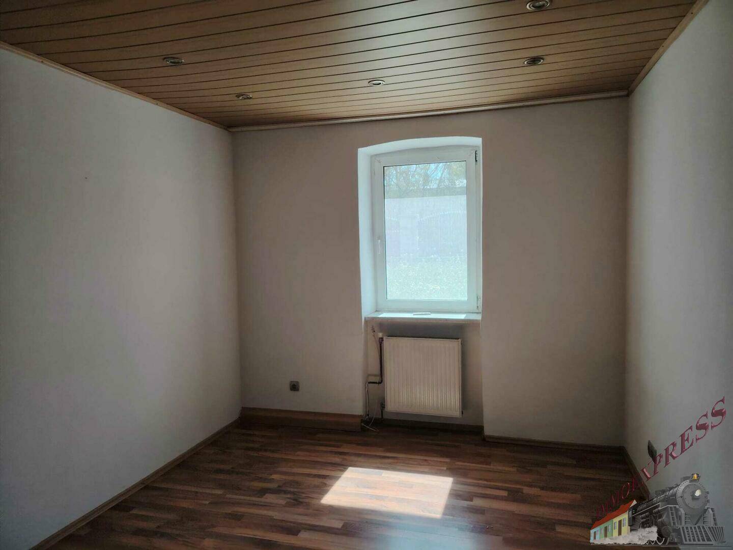 Schlafzimmer mit Holztäfelung an der Decke, Laminatboden und einem Fenster.