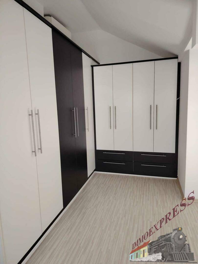 Ankleidezimmer mit maßgefertigten Einbauschränken in Schwarz-Weiß und Laminatboden.
