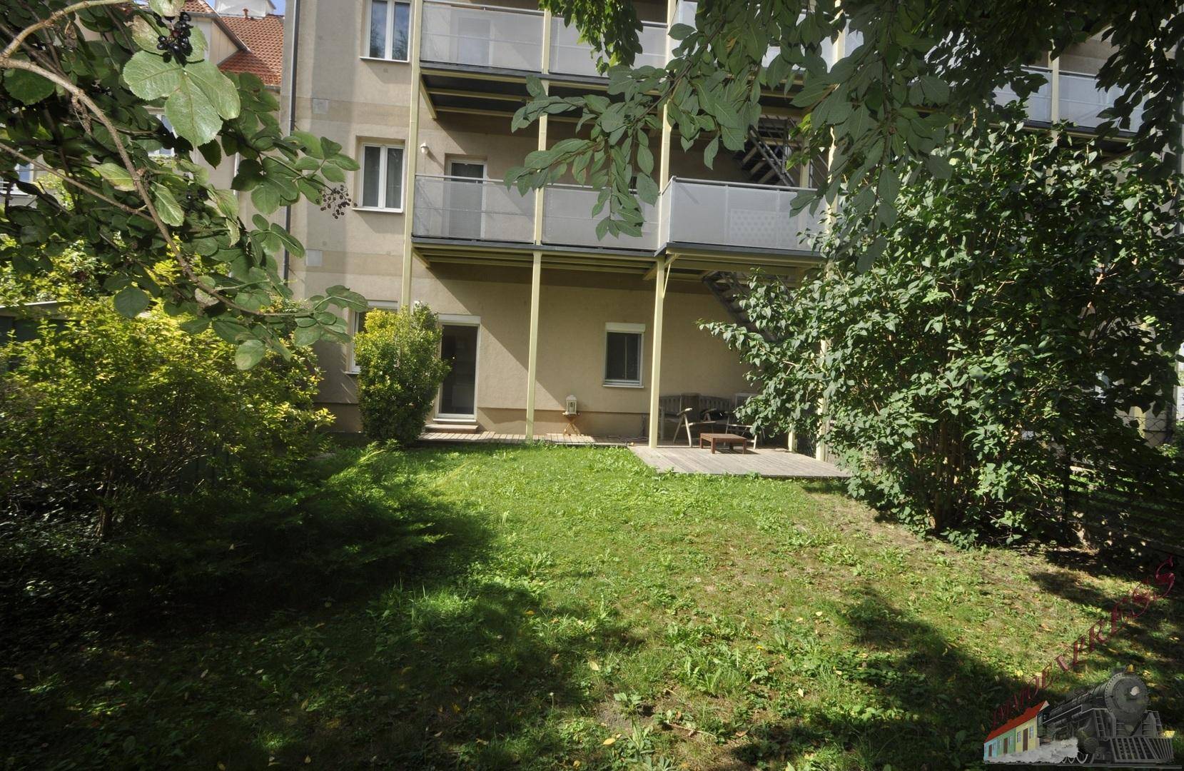 Gepflegter Gartenbereich vor dem Gebäude mit Balkonen und Grünflächen.
