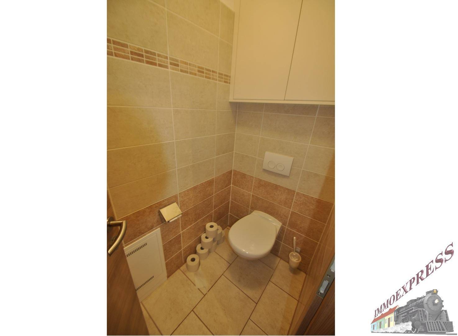 Separates WC mit Wandtoilette und praktischen Hängeschränken.