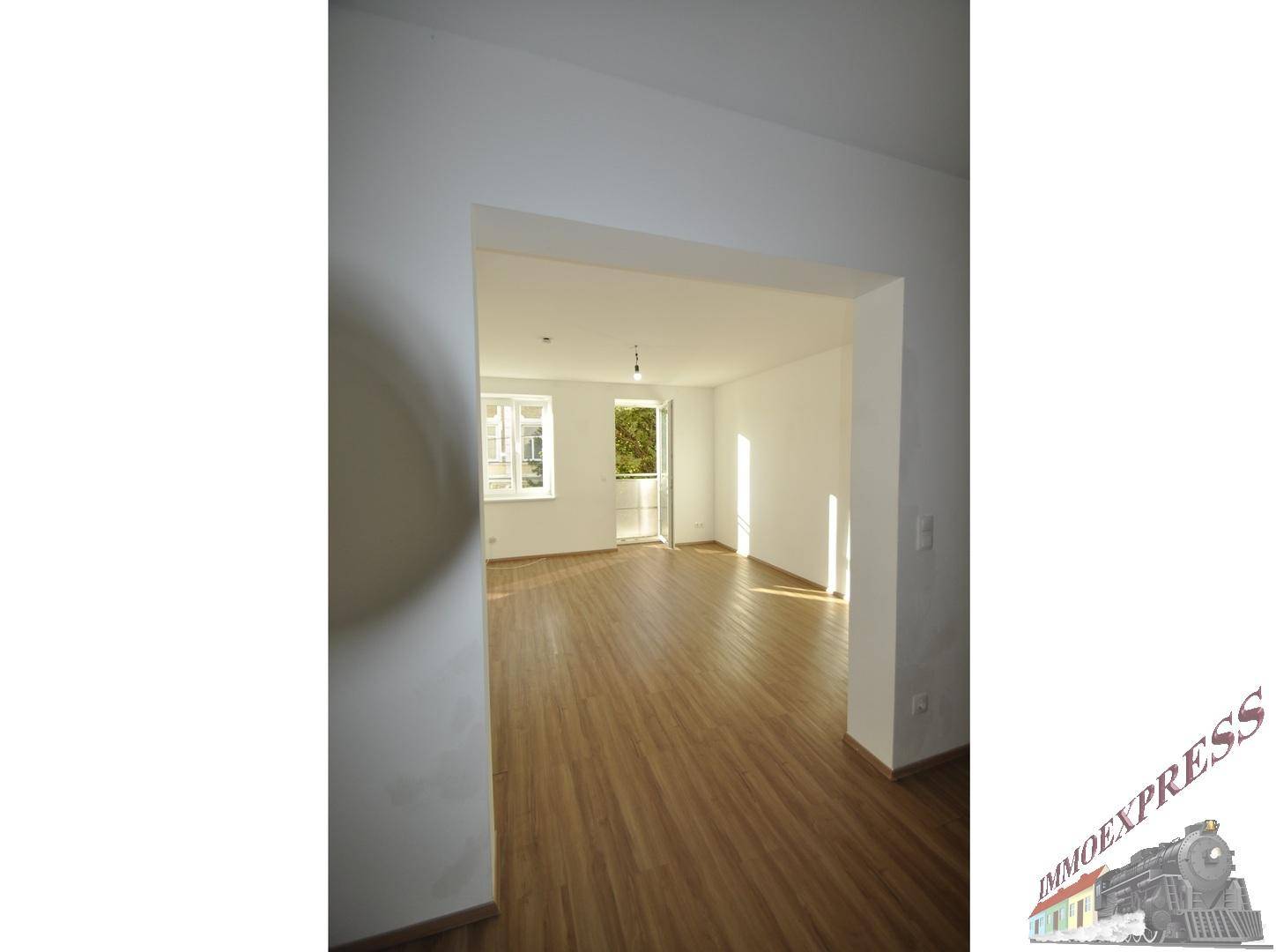 Geräumiger Wohnbereich mit Laminatboden und viel Tageslicht, ideal für individuelle Gestaltung.