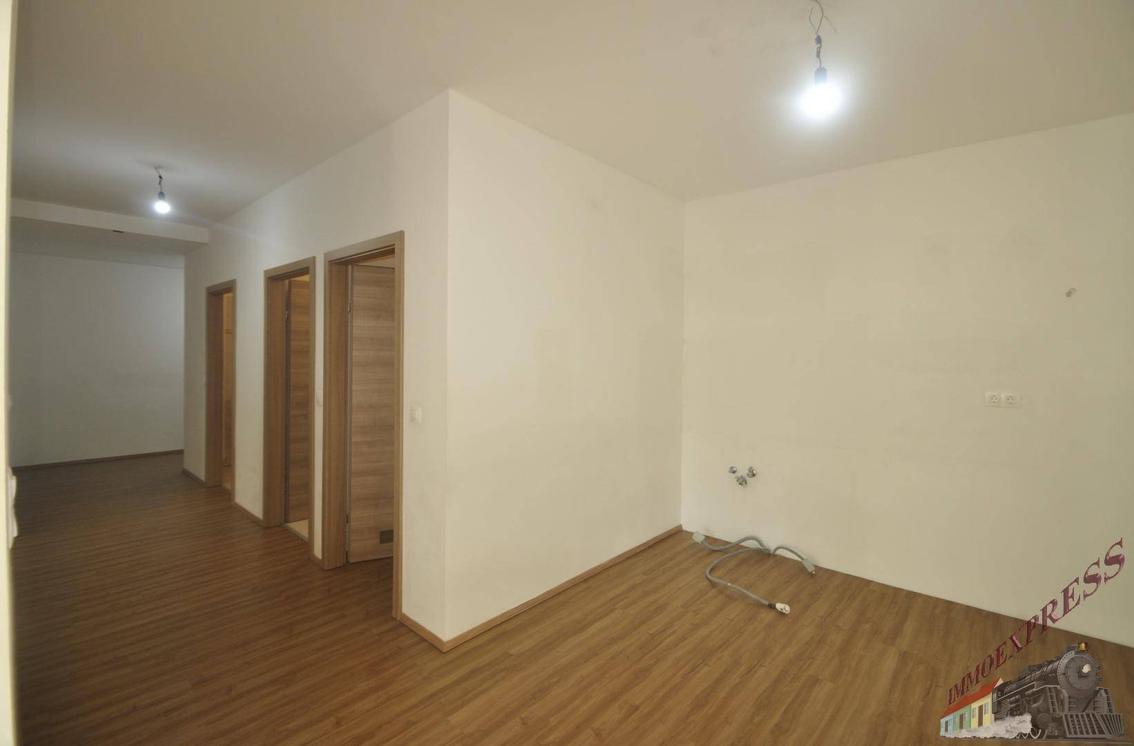 Heller Flur mit Laminatboden und mehreren Türen, führt zu weiteren Räumen.
