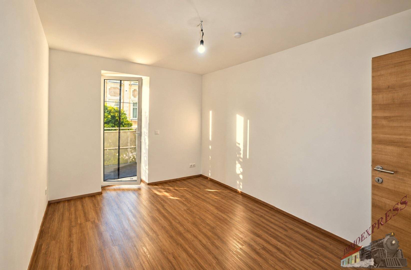 Helles Zimmer mit Laminatboden und Zugang zu einem französischen Balkon oder kleiner Terrasse.