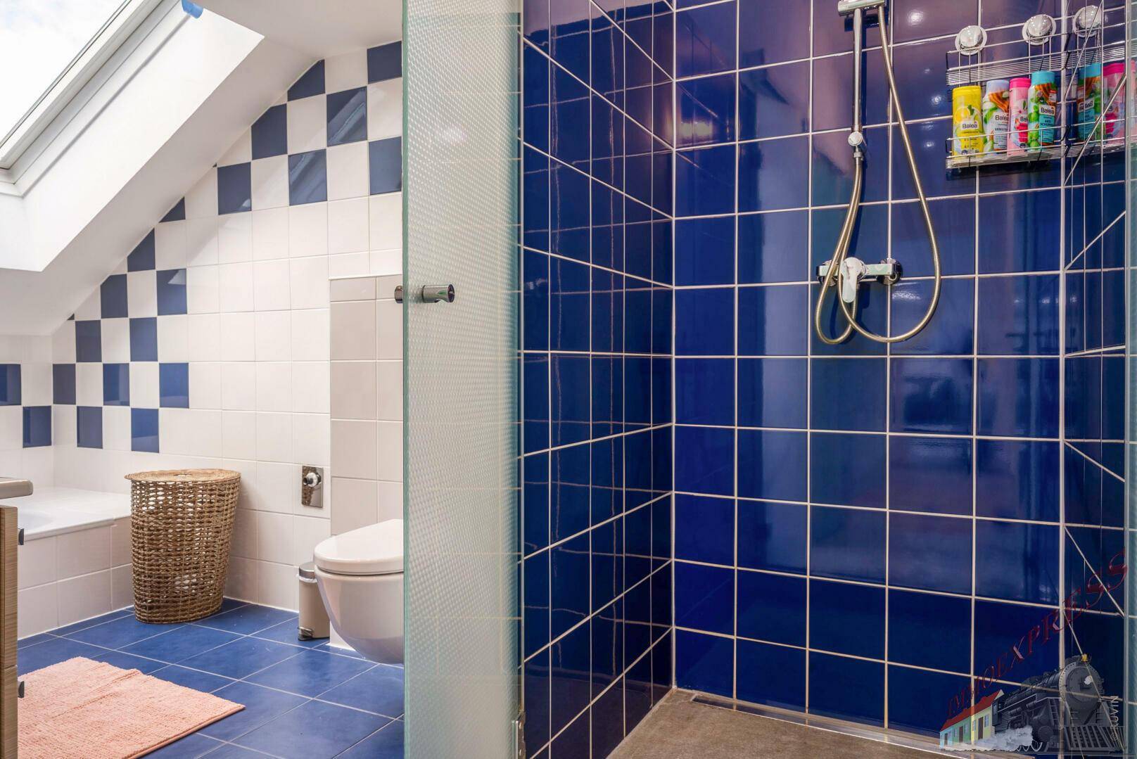 Badezimmer im Dachgeschoss mit Dusche, WC und blau-weißen Fliesen.