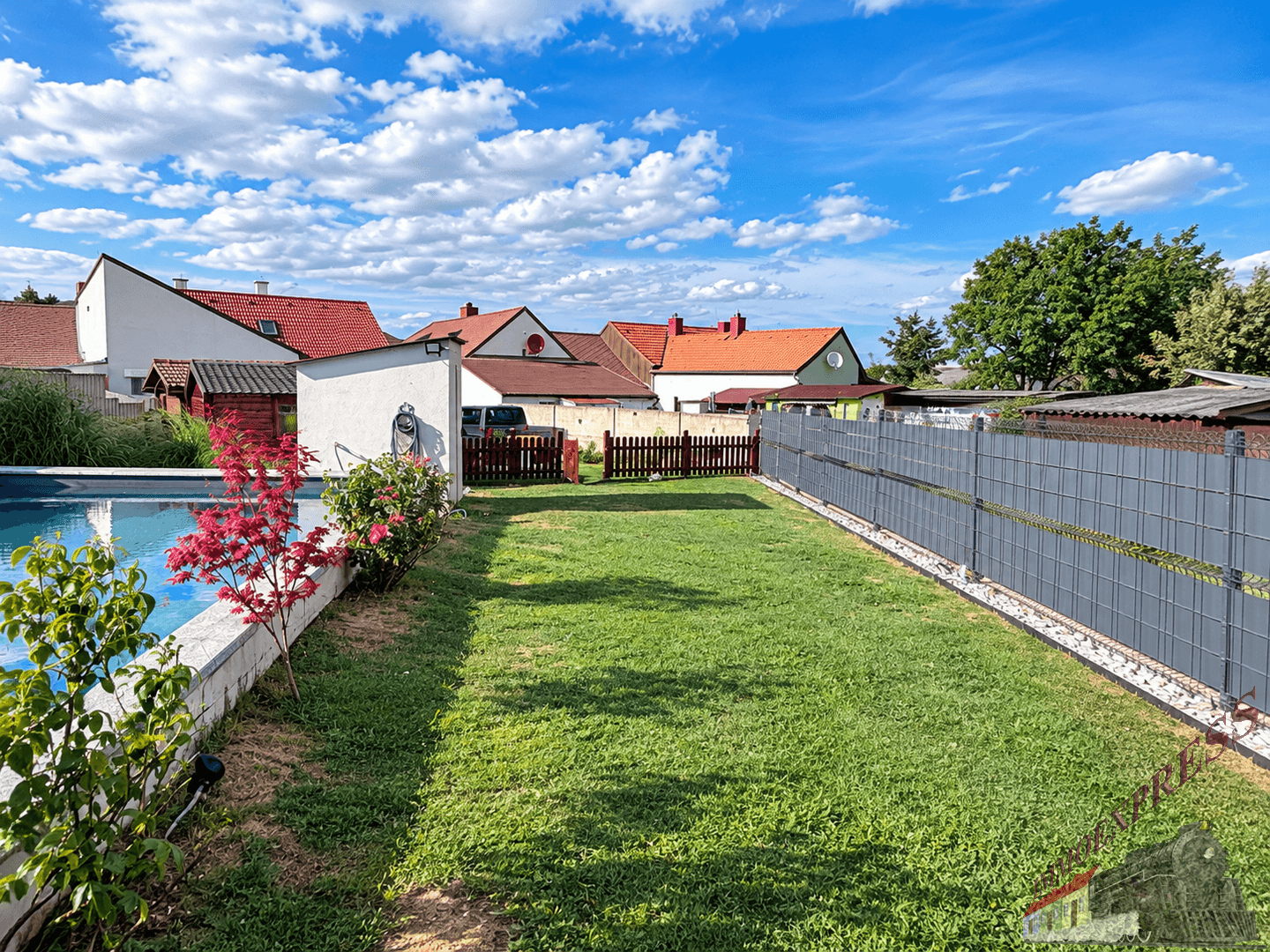 Gepflegter Garten mit Rasenfläche, Pool und Blick auf die umliegenden Häuser.