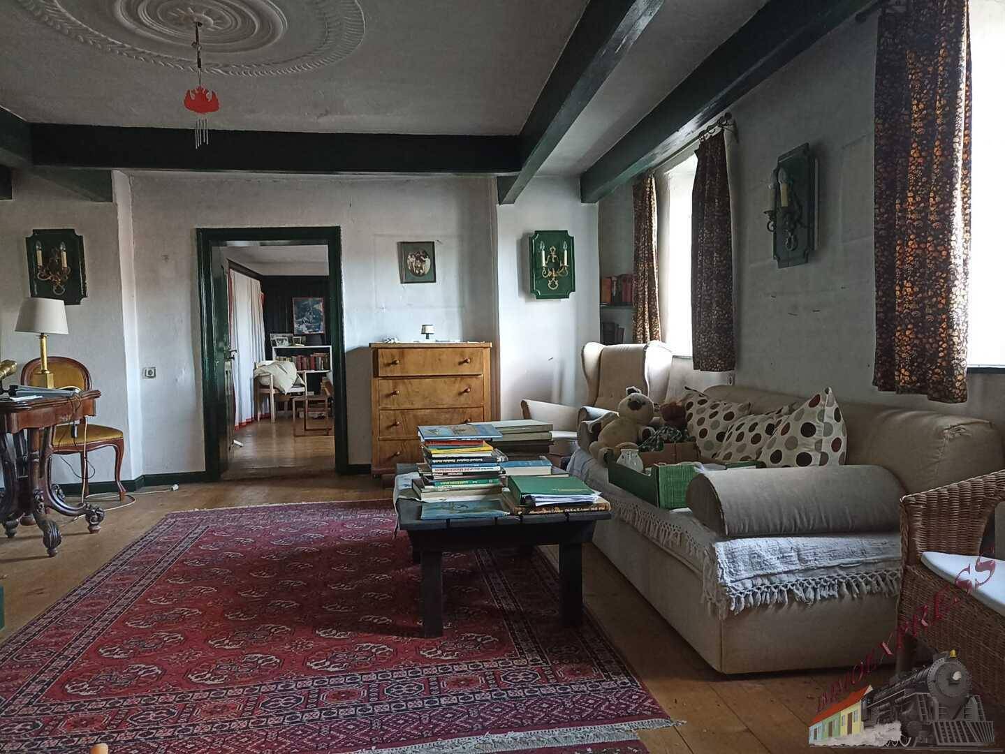 Gemütliches Wohnzimmer mit Holzboden, Teppich und traditioneller Einrichtung.