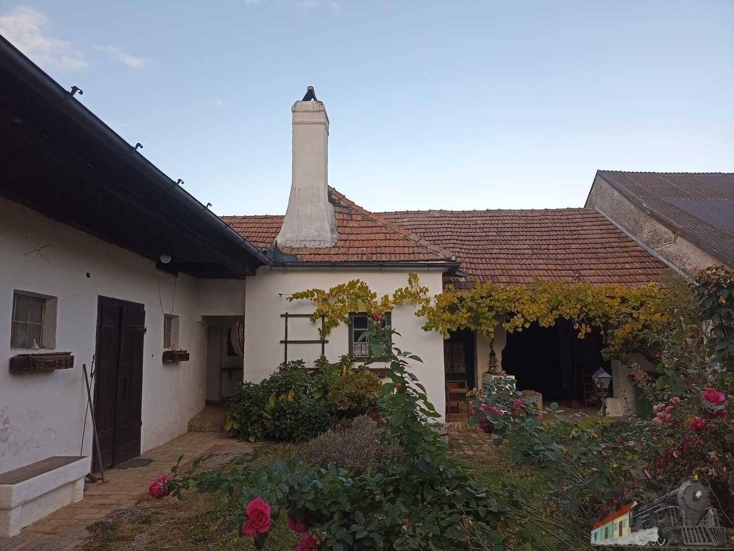 Idyllischer Innenhof mit Rosenbeeten, Kamin und traditioneller Architektur.