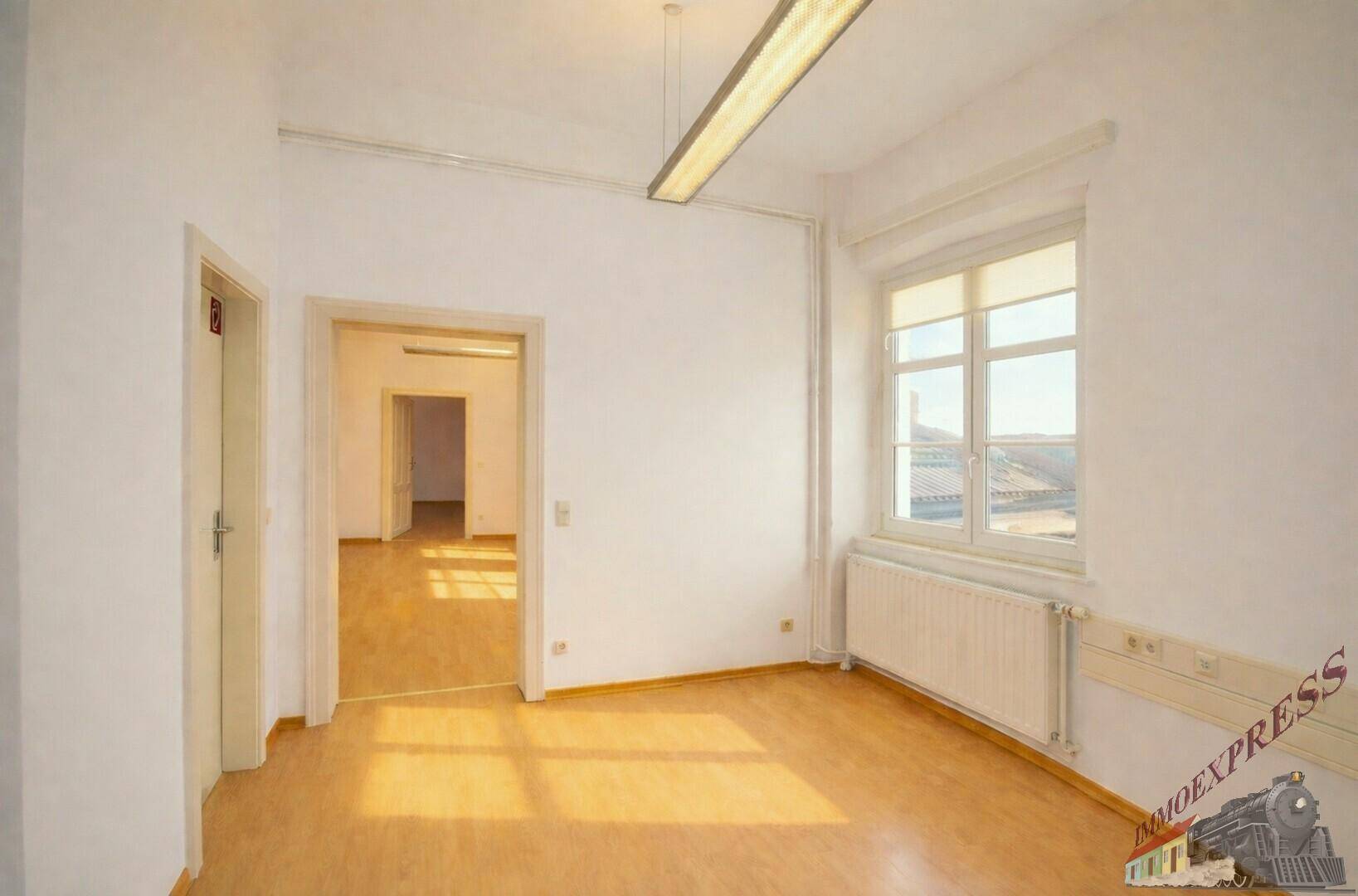 Geräumiger, heller Raum mit Holzboden, großem Fenster und Heizkörper, bereit zur individuellen Gestaltung.