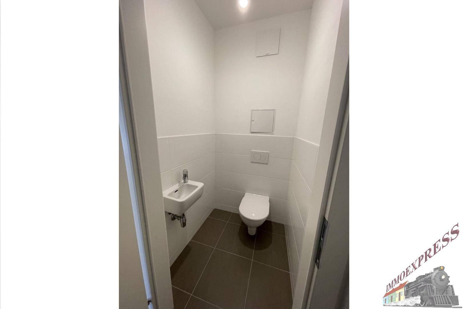 Separates Gäste-WC mit wandhängender Toilette und kleinem Handwaschbecken.