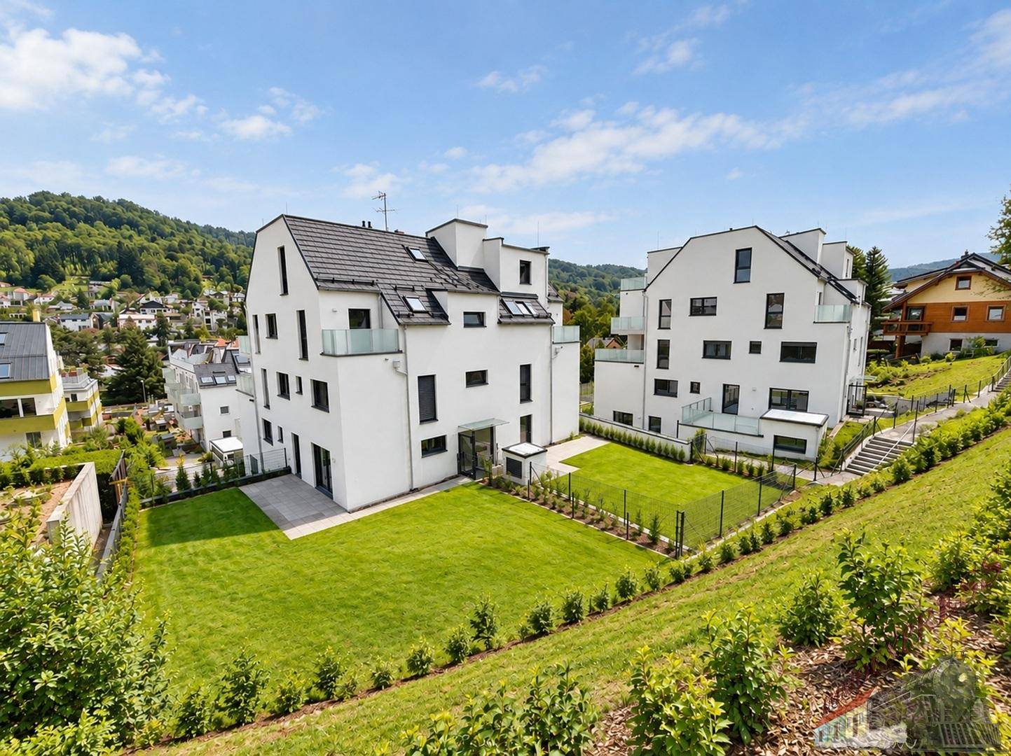 Moderne Wohnanlage mit gepflegten Rasenflächen und Blick auf die grüne Umgebung.