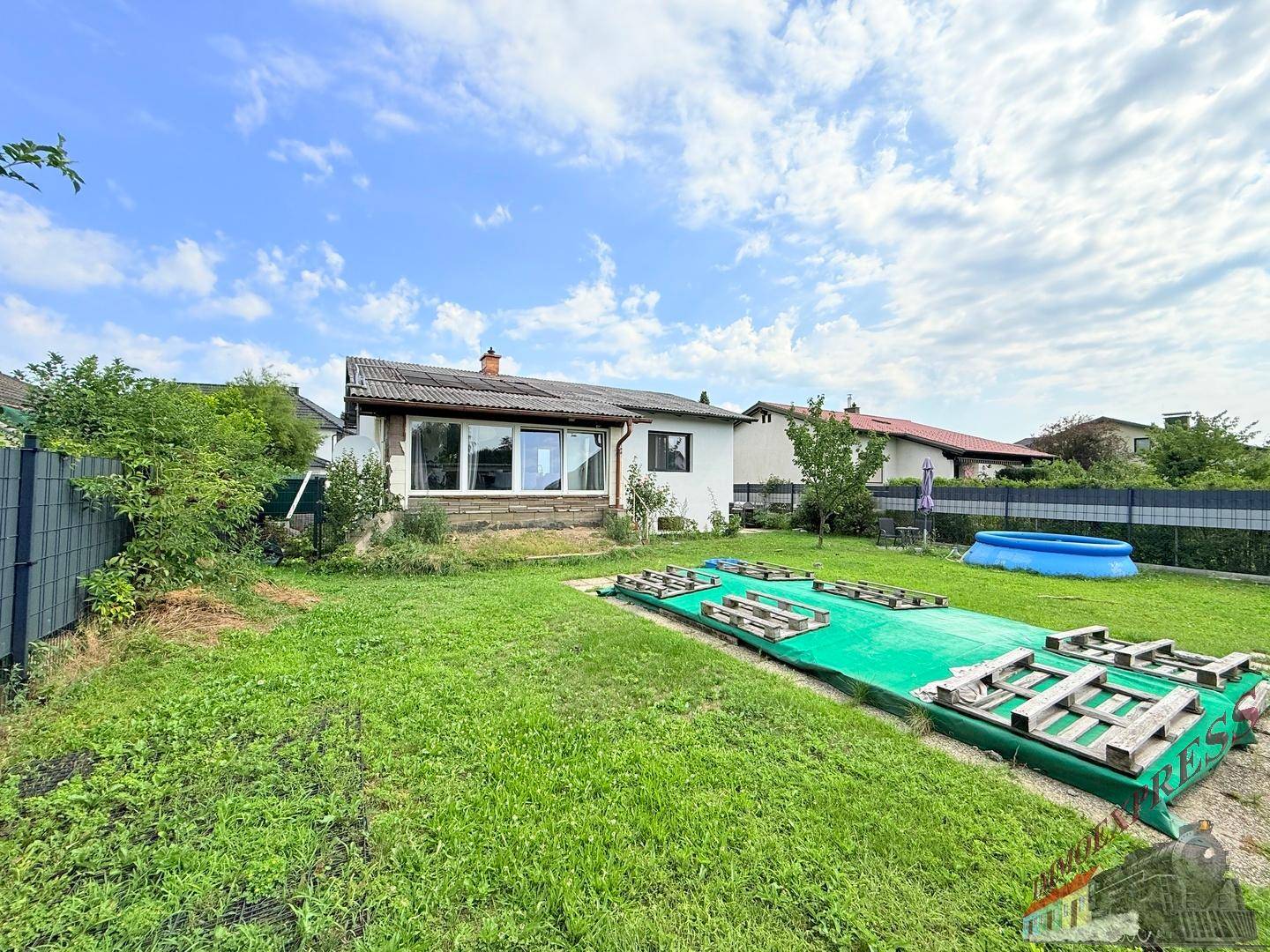 Großer Garten mit Rasenfläche, kleinem Pool und Blick auf das Einfamilienhaus.