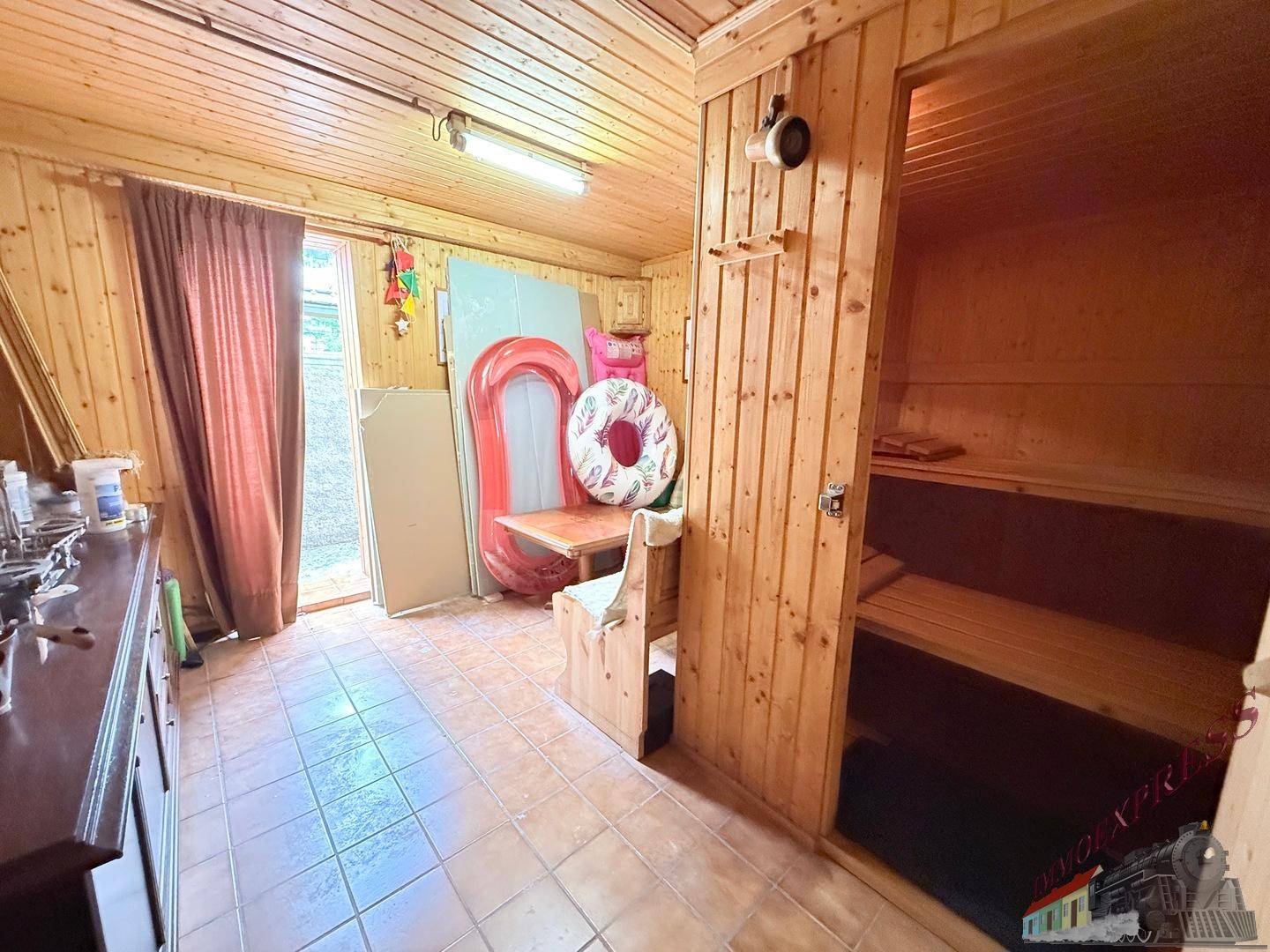Rustikaler Raum mit Holzverkleidung, Fliesenboden und integrierter Sauna für Wellness.
