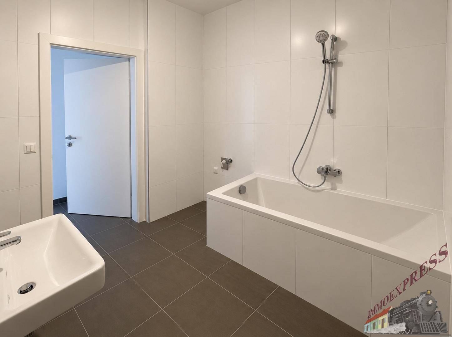 Modernes Badezimmer mit Badewanne, Duscharmatur und großformatigen Fliesen.