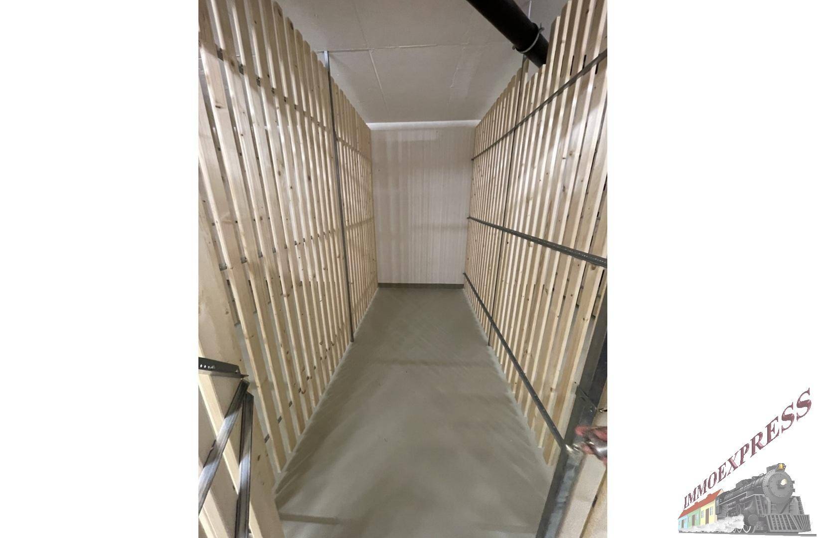 Abstellraum mit Holzlattenwänden und Betonboden für zusätzlichen Stauraum.