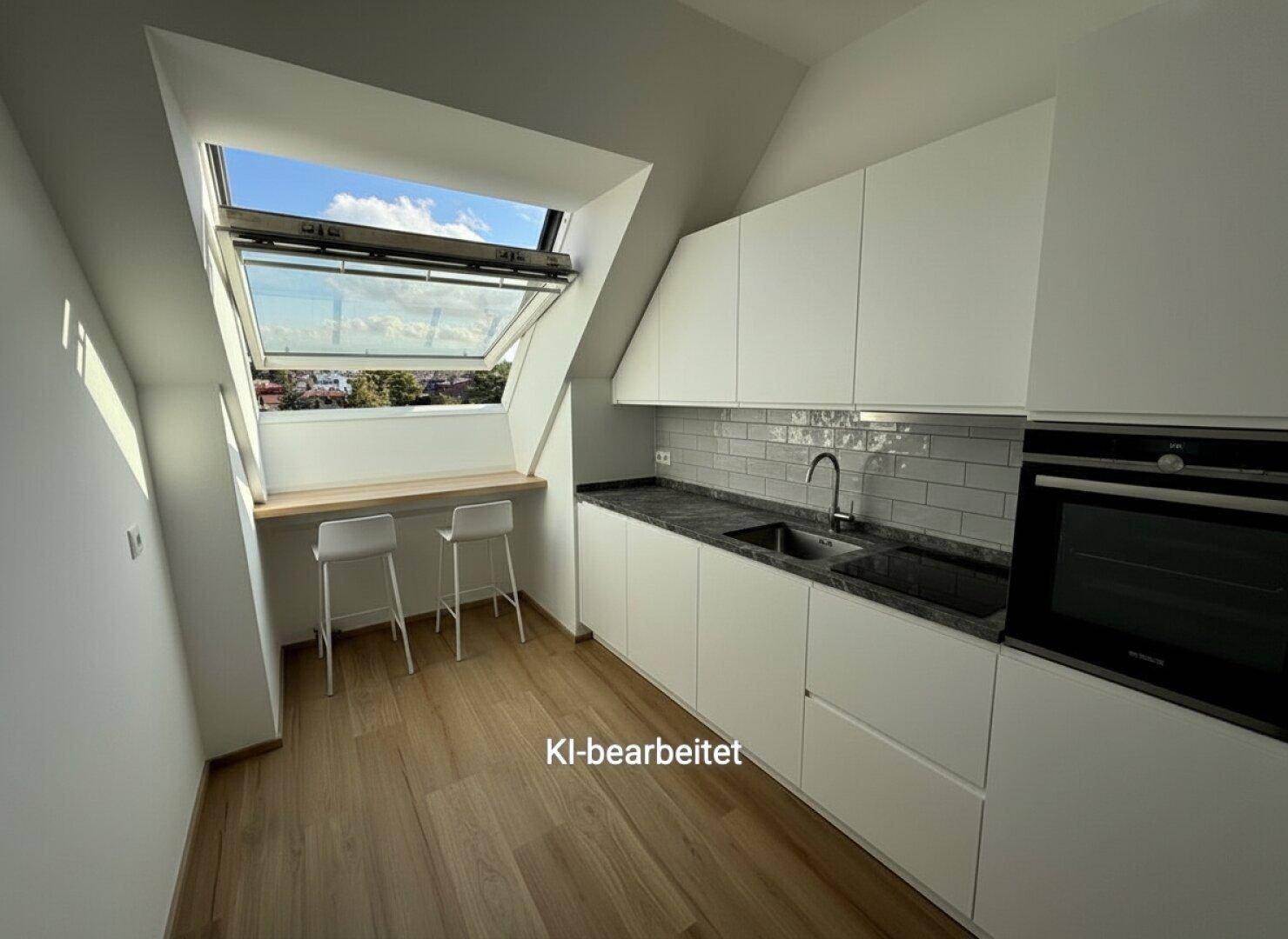 Moderne Küche im Dachgeschoss mit weißen Schränken, dunkler Arbeitsplatte und Dachfenster.