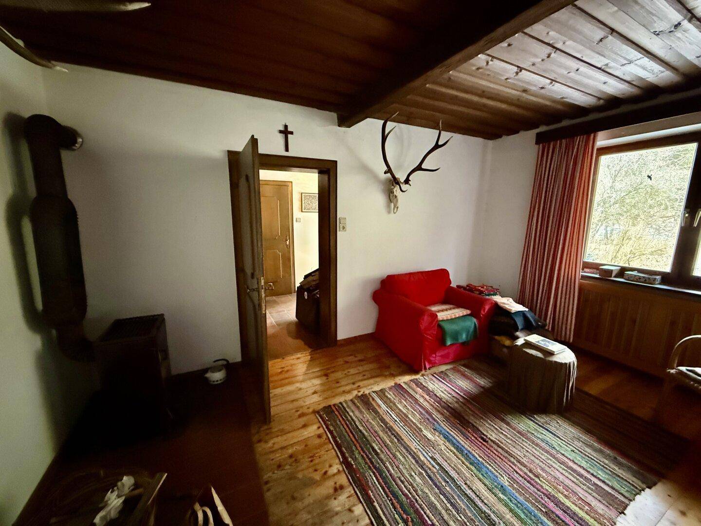 Schlafzimmer mit Holzdielenboden, Holzofen und traditioneller Einrichtung im Landhausstil.