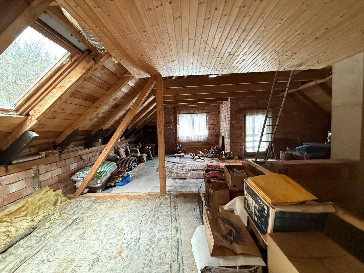 Ausgebauter Dachboden mit Holzverkleidung, Dachfenstern und Stauraum.