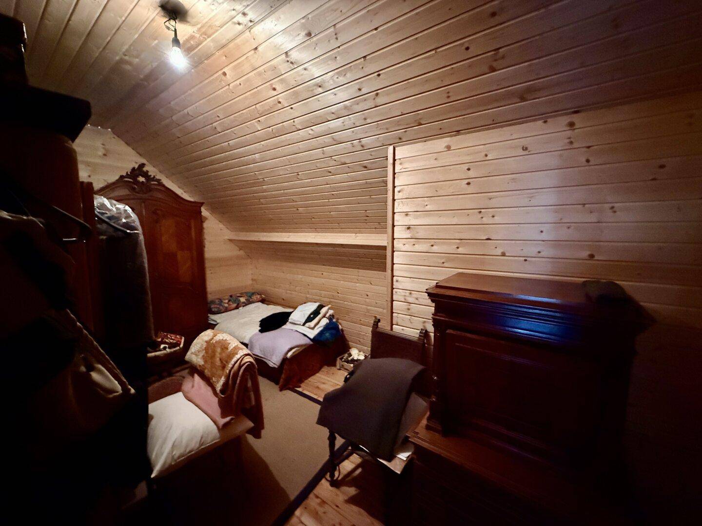 Kleiner Schlafbereich im Dachgeschoss mit Holzverkleidung und traditionellen Möbeln.